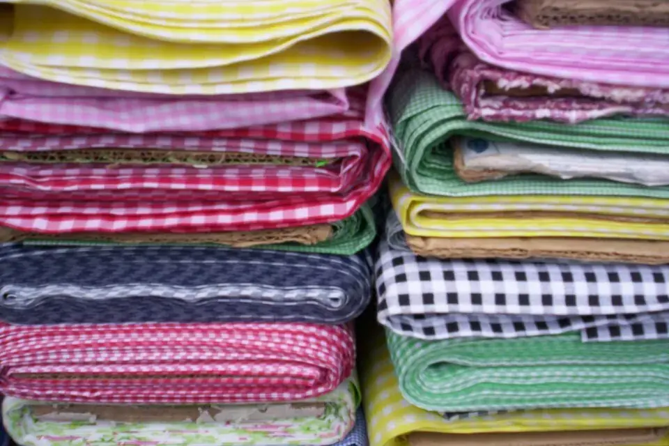 Piles de tissus pliés en vichy et en carreaux, rose, vert, jaune, bleu et noir et blanc