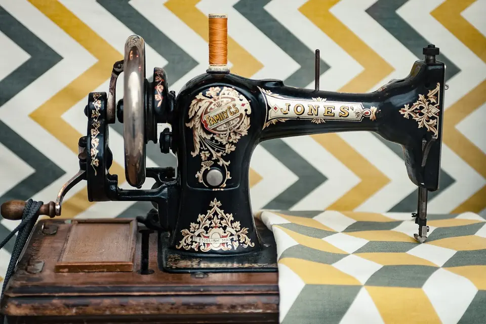 Ancienne machine à coudre noire à décor doré posée sur une table en bois
