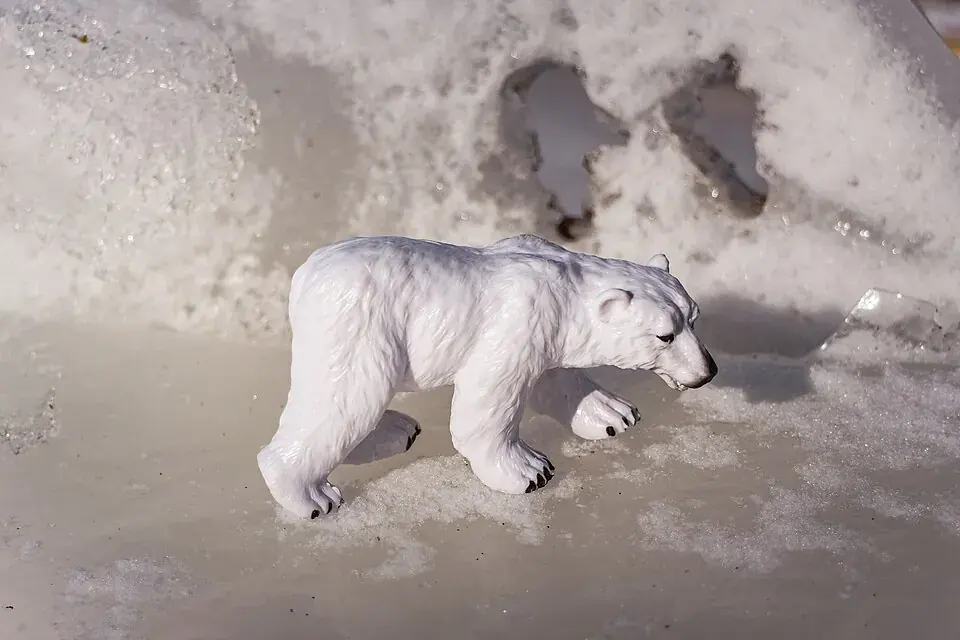 Figurine d'ours blanc posée sur la neige devant un bloc de glace
